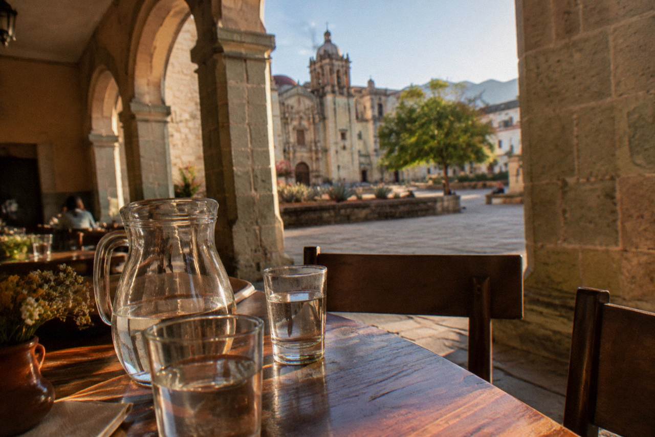 Water glasses and a large water jug on a cafe table in a colonial arcade in Oaxaca City