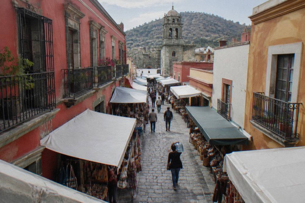 A shopper carrying a large sealed water jug through a market corridor in Oaxaca