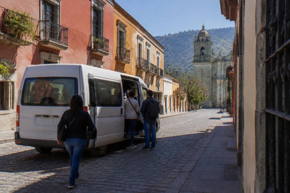 A colectivo van loading passengers on a street in Oaxaca City