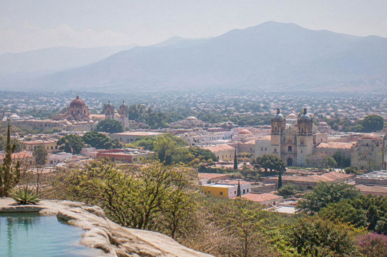 A view over the tiled roofs and church domes of Oaxaca City with mountains behind