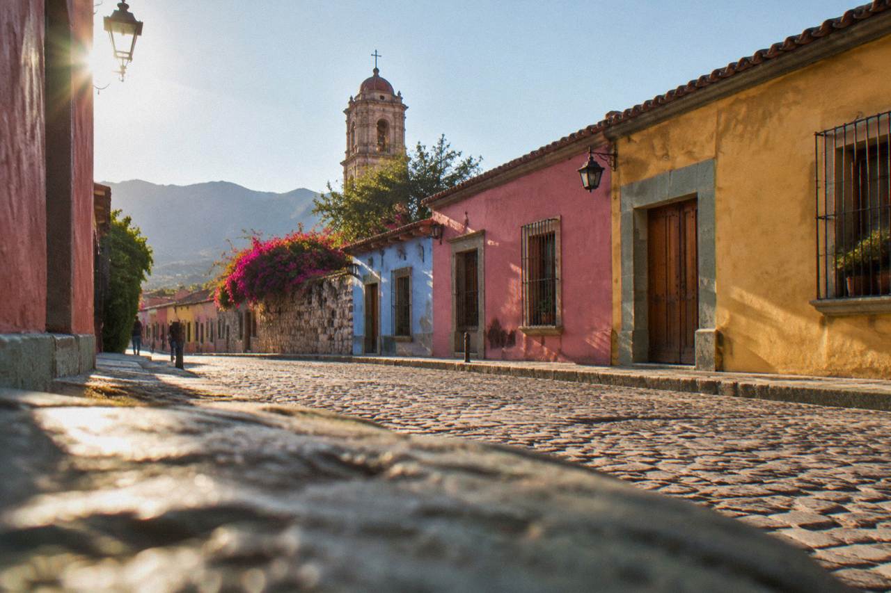 A colonial street in Oaxaca City with colourfully painted facades under an afternoon sky
