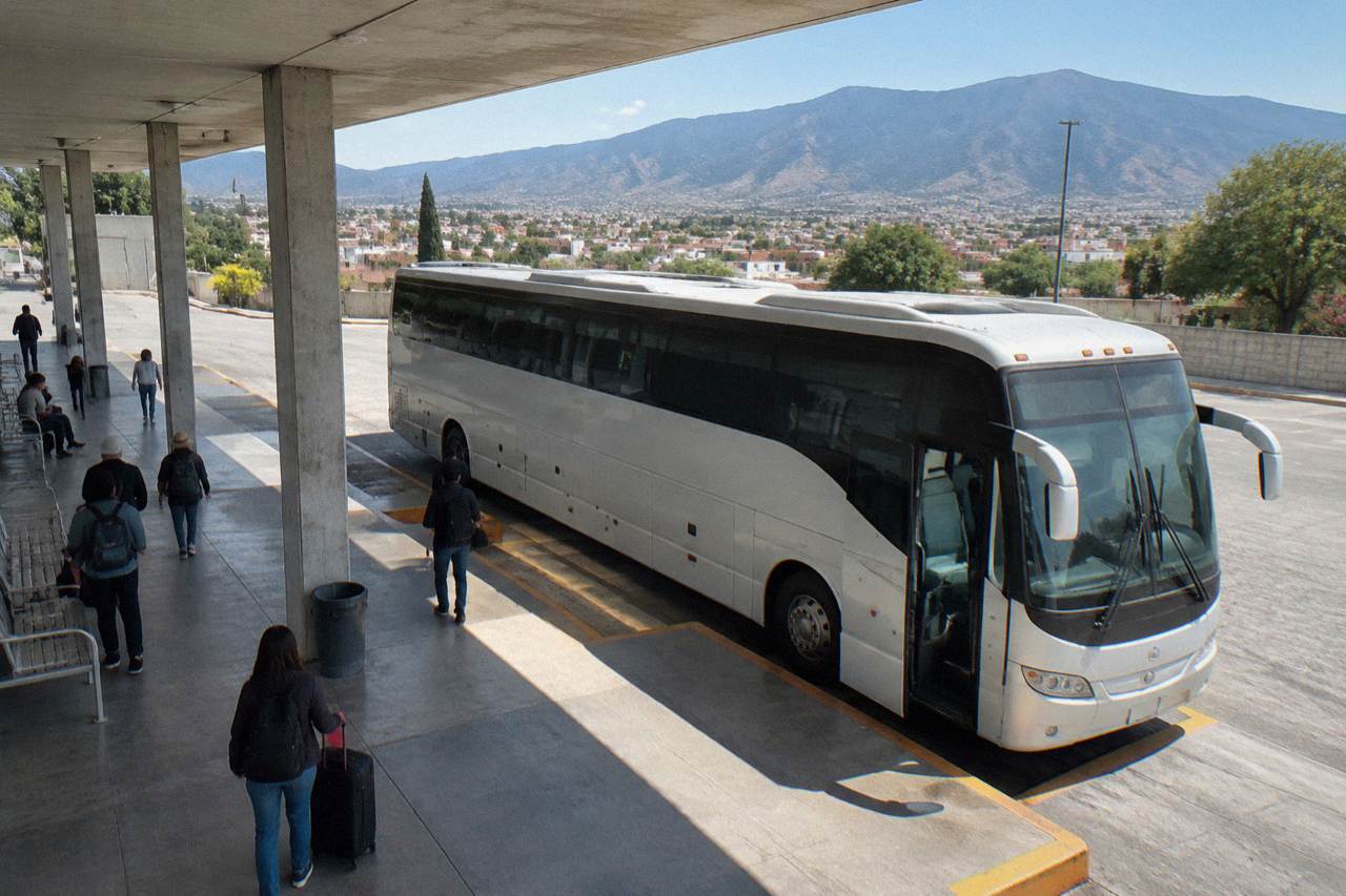 A long-distance bus parked at a terminal in Mexico with mountains in the distance