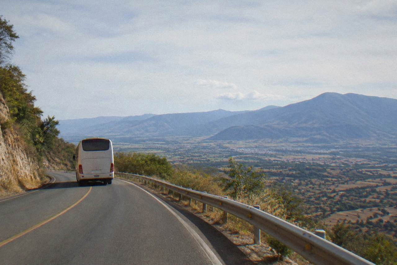 A bus winding along a mountain road toward Oaxaca City in the late afternoon