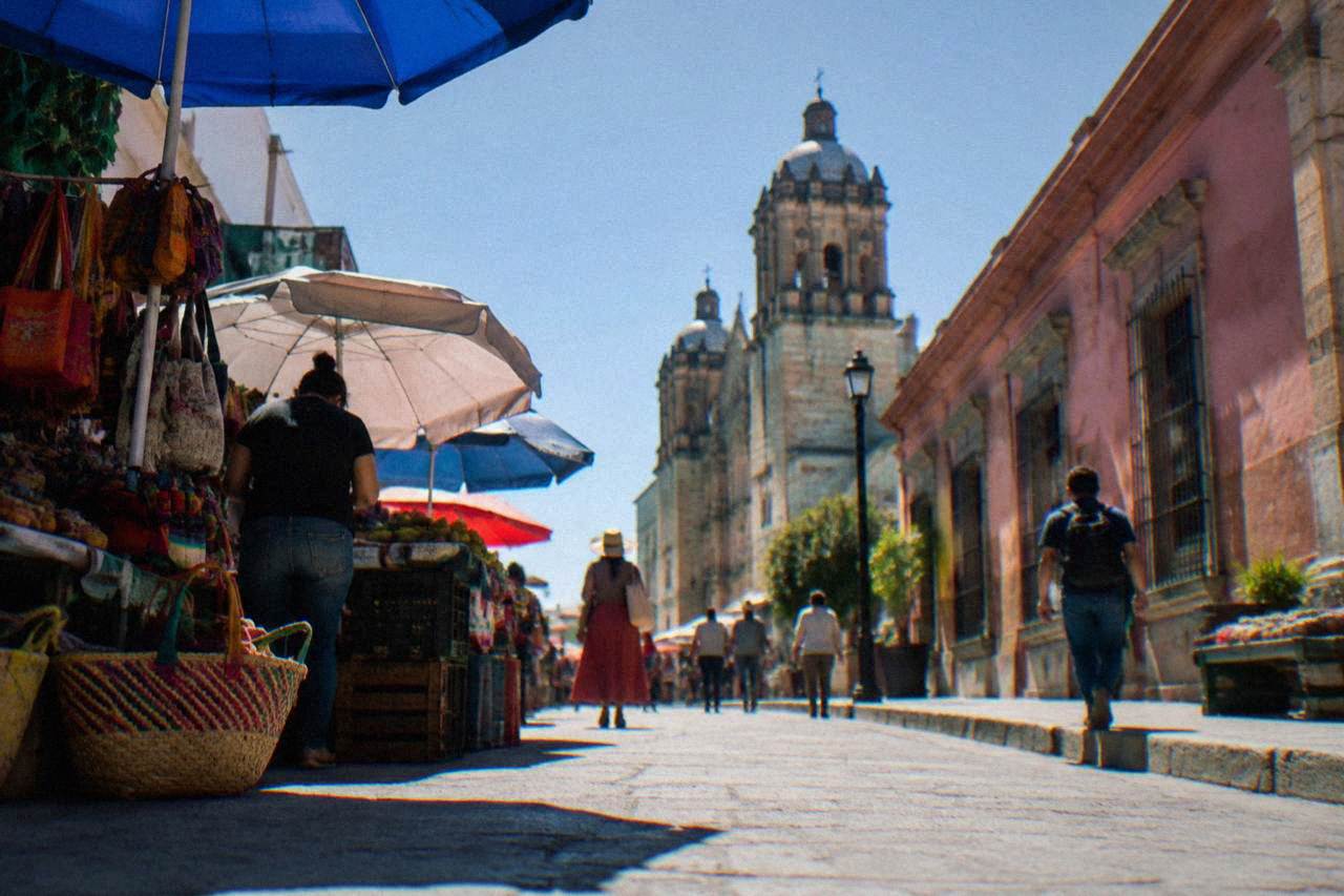 A busy market street in Oaxaca City with vendors and colonial buildings in the background