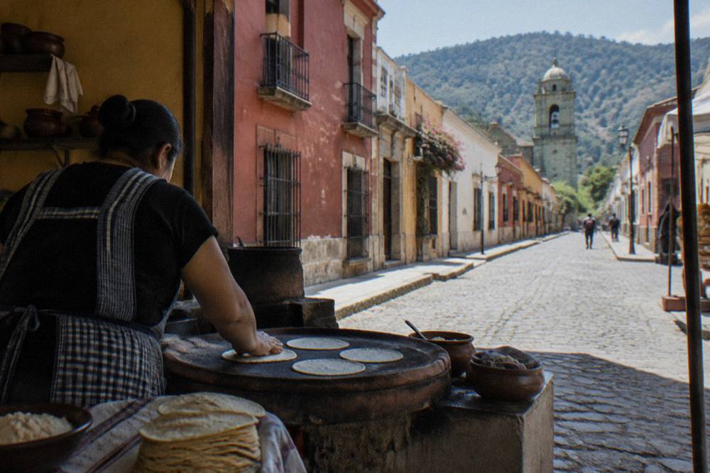 A cook pressing fresh tortillas on a clay comal in an Oaxacan market kitchen