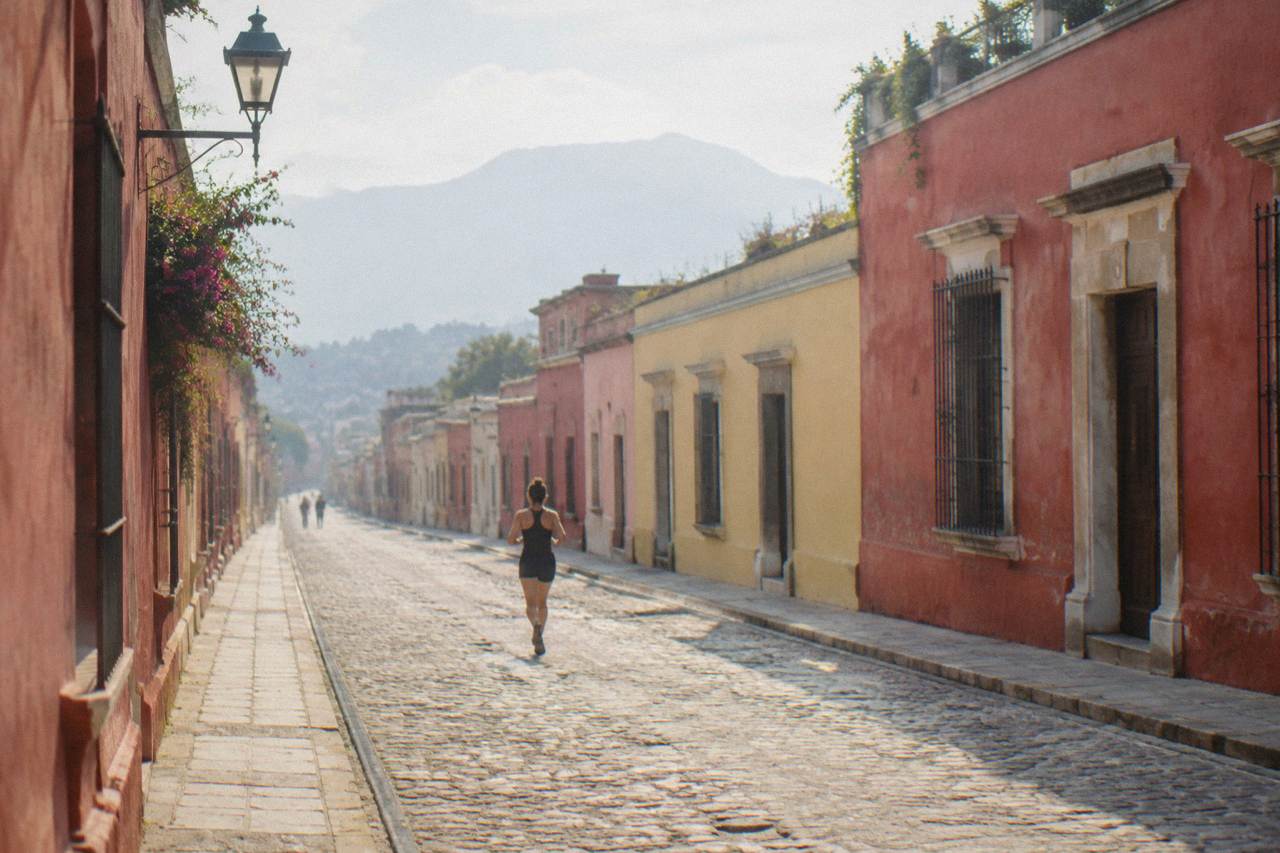 A quiet colonial street in Oaxaca City with colorfully painted buildings in late afternoon light