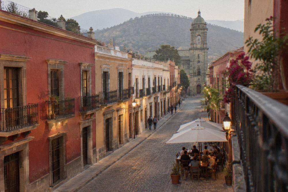 People dining at an outdoor table on a warmly lit Oaxaca street in the evening