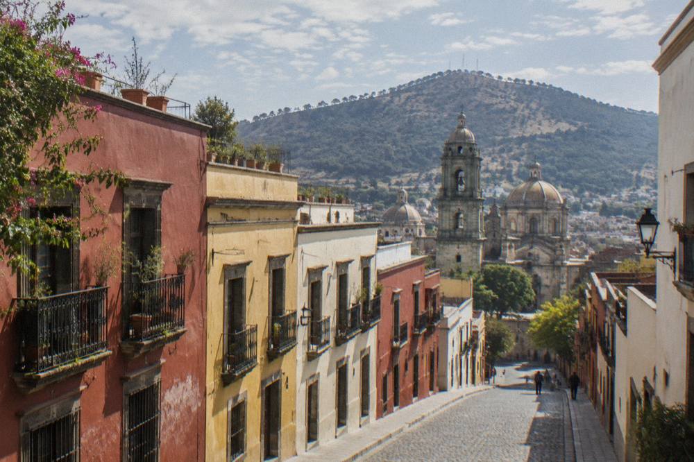 Sunlight over rooftops and church domes in Oaxaca City seen from a hillside