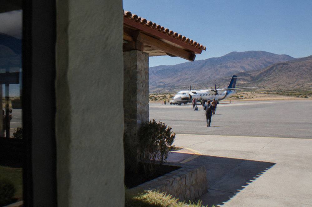 A plane on a small airport apron with dry highland hills behind it