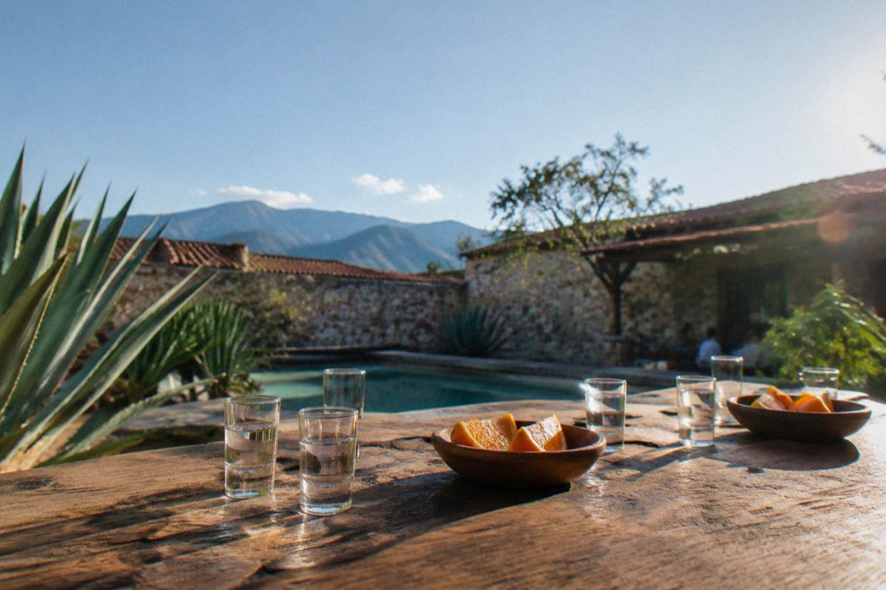 Glasses of mezcal and orange slices arranged on a wooden tasting table in Oaxaca