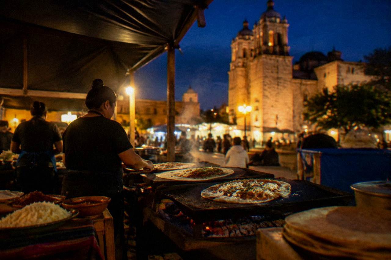 A busy food stall grilling large tlayudas at night in Oaxaca City