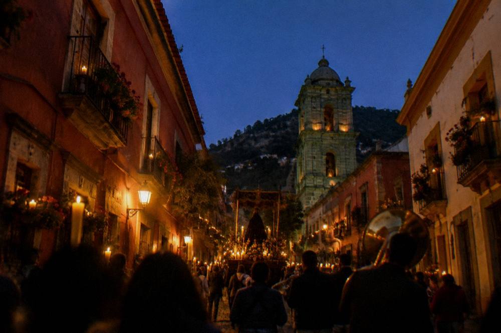Procession with candles and music moving through a decorated Oaxaca street at night