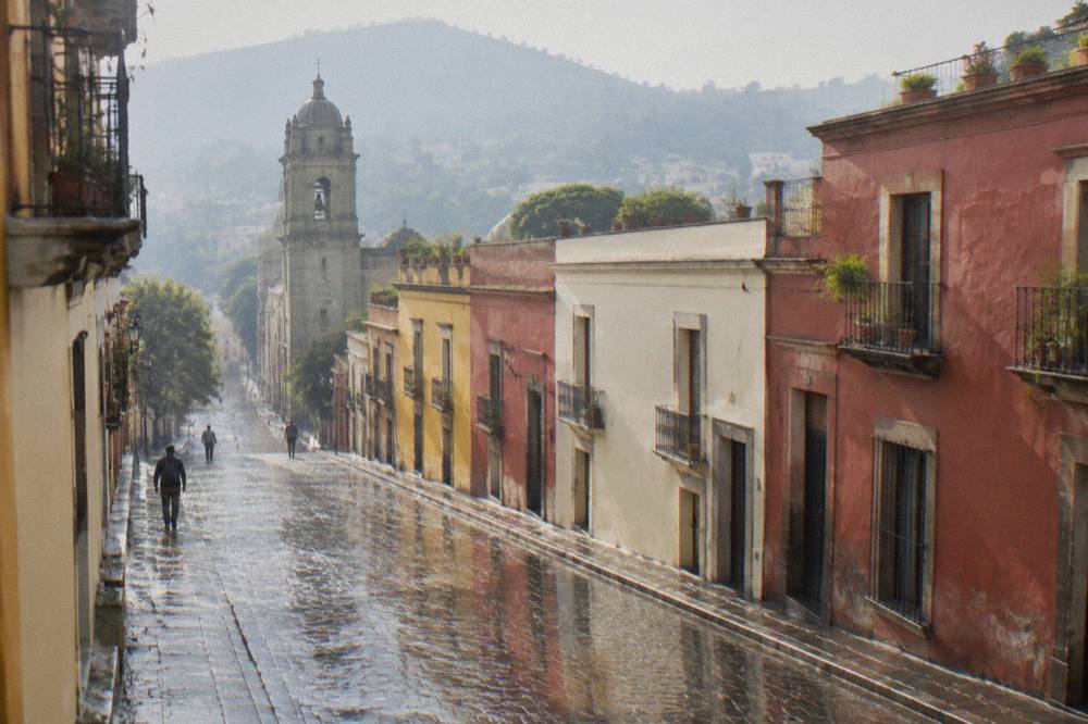 A wet cobblestone street in Oaxaca reflecting colourful building facades after an afternoon shower