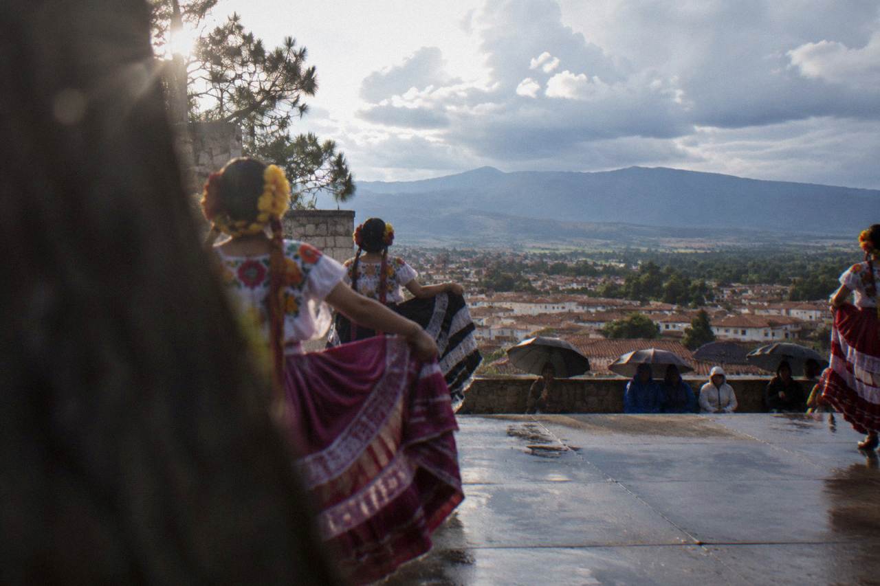 Dancers in regional Oaxacan costume performing on an outdoor stage during a summer festival