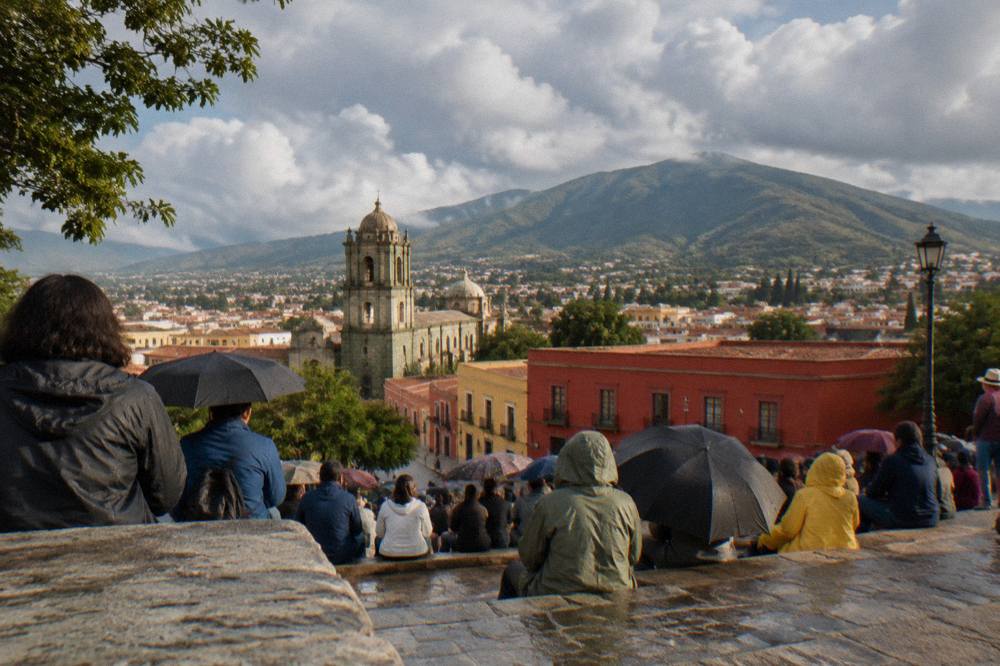 Crowds gathered on a hillside auditorium terrace overlooking Oaxaca City on a summer afternoon