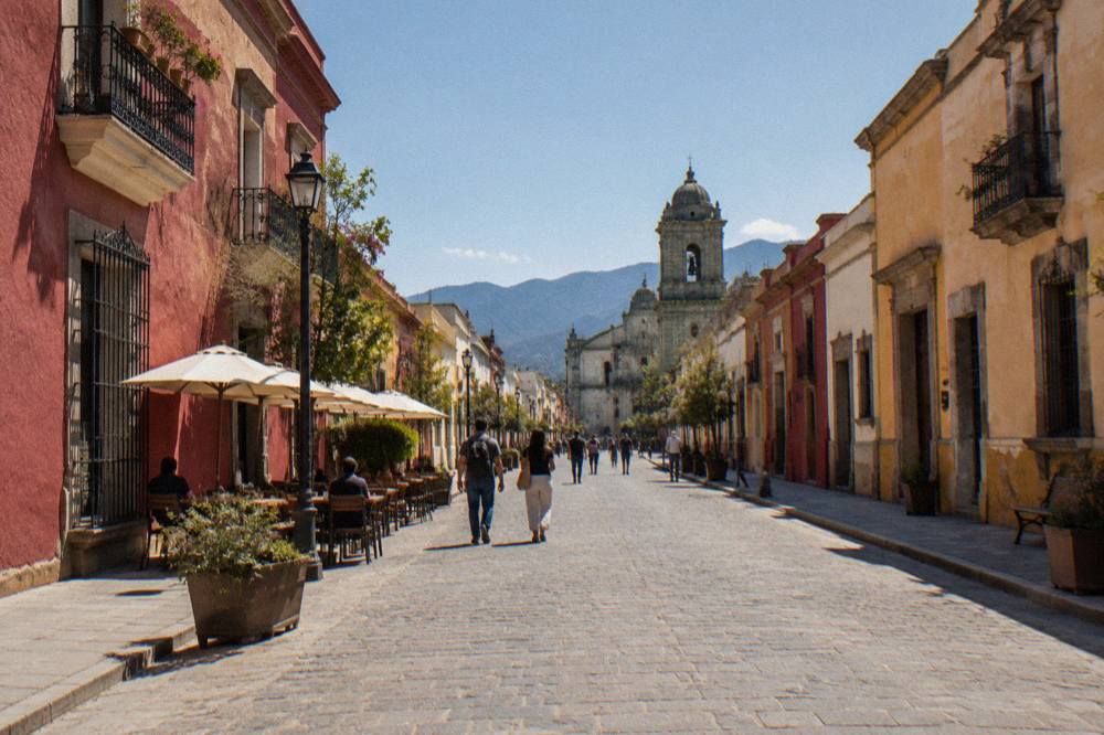 A pedestrian street with colonial facades and people walking in late afternoon light