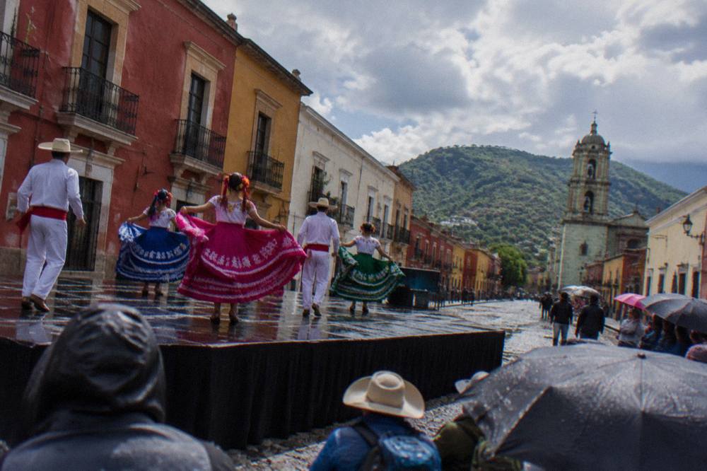 Dancers in regional costume performing on an outdoor stage in Oaxaca during a summer festival
