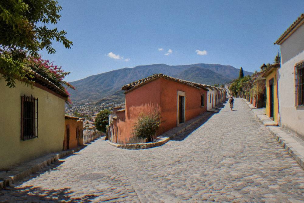 A wide shot of a Jalatlaco street in Oaxaca City with painted walls on both sides