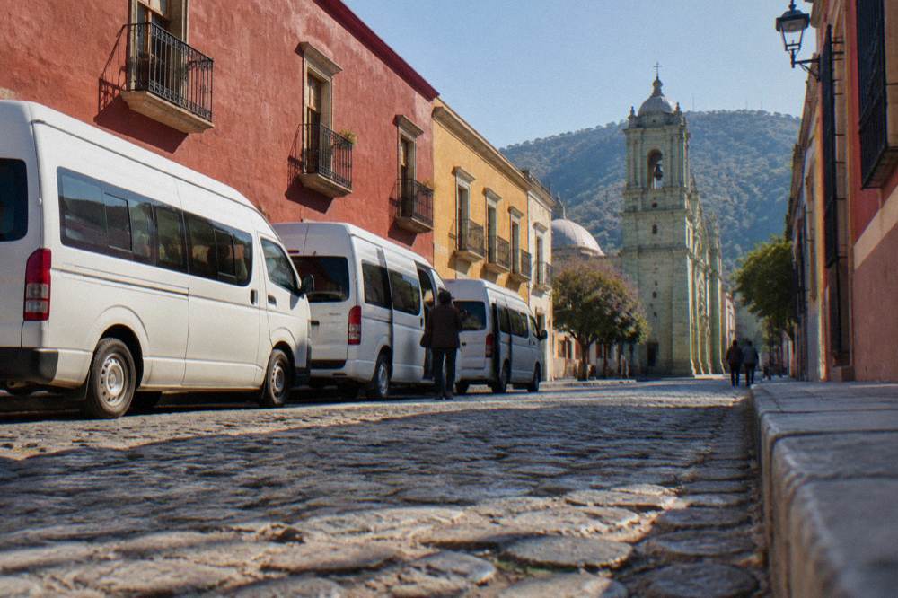 Shared vans parked at a colectivo rank on a street in southern Oaxaca City