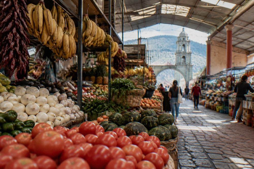 A covered market hall in Oaxaca City with food stalls and hanging produce