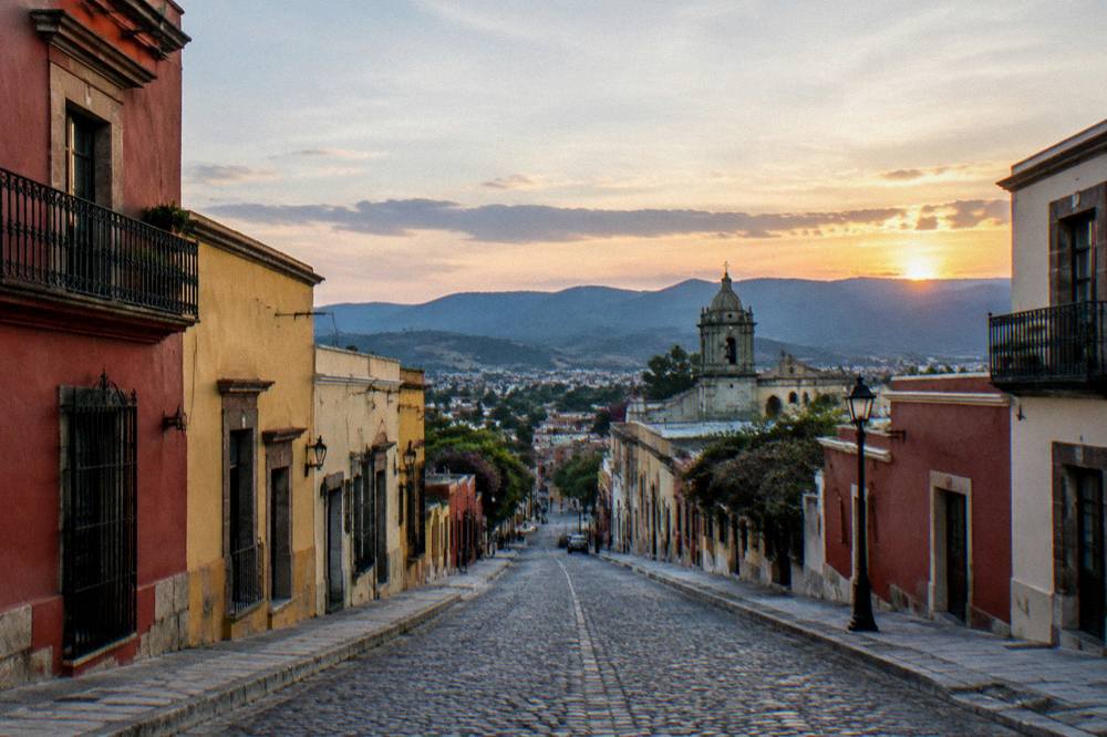 A view across Oaxaca City rooftops toward the valley hills at sunset