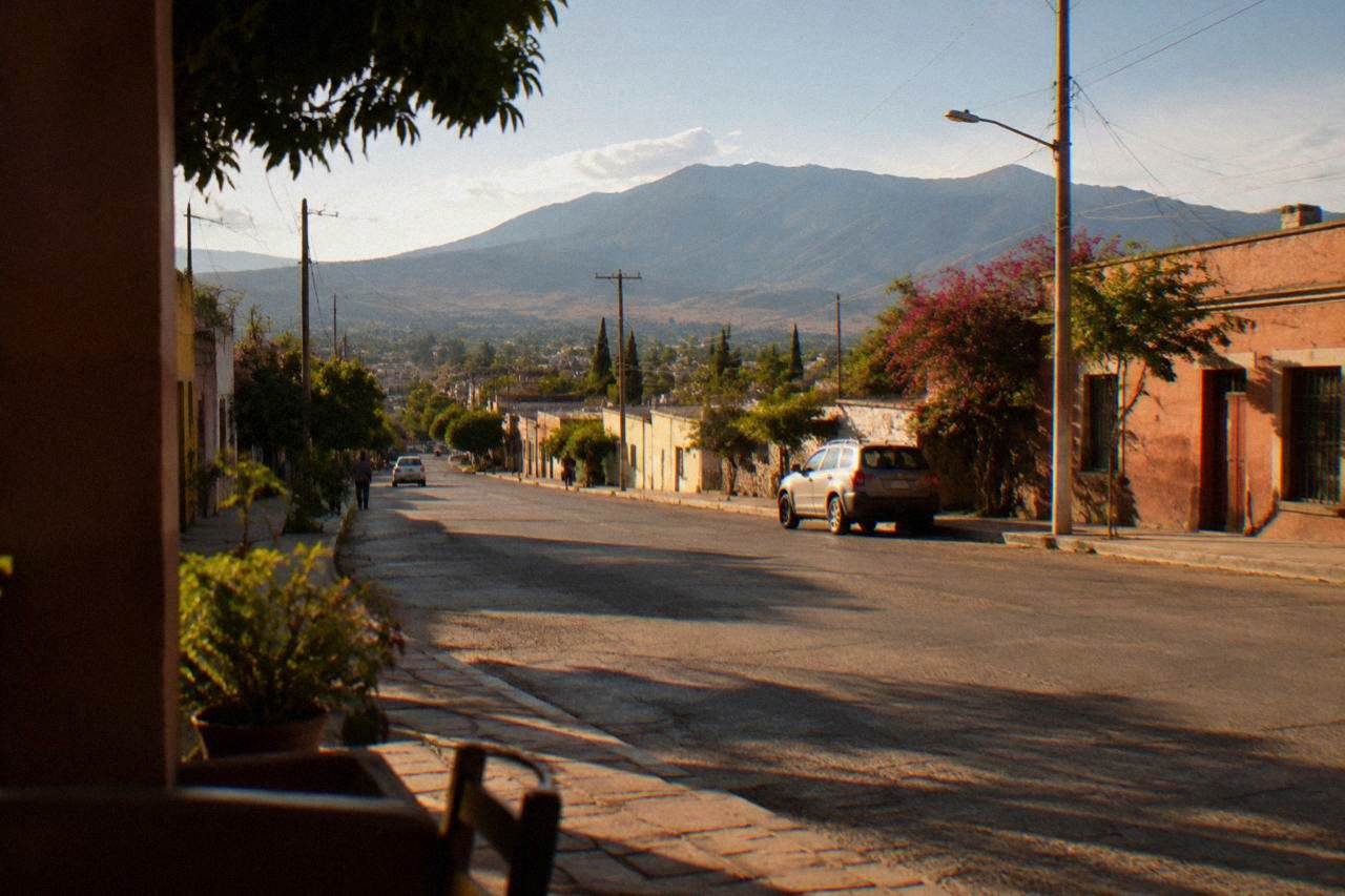 Street scene on the southern edge of Oaxaca City with low buildings and hills in the distance