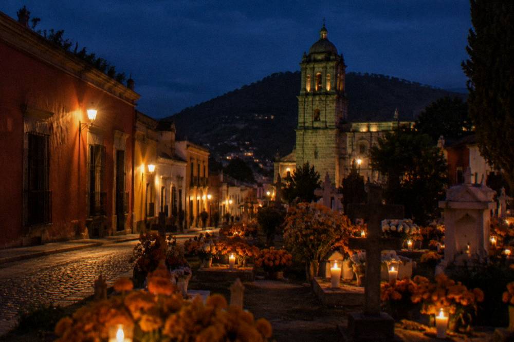 Cemetery at dusk with marigold flowers and candles on graves in Oaxaca