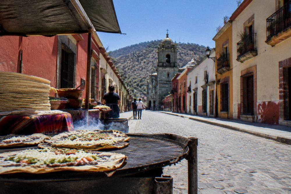 Food stall with tlayudas grilling and stacks of tortillas in an Oaxaca market