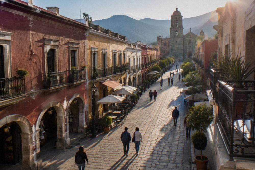 People walking along a wide pedestrian street with colonial arcades and shopfronts