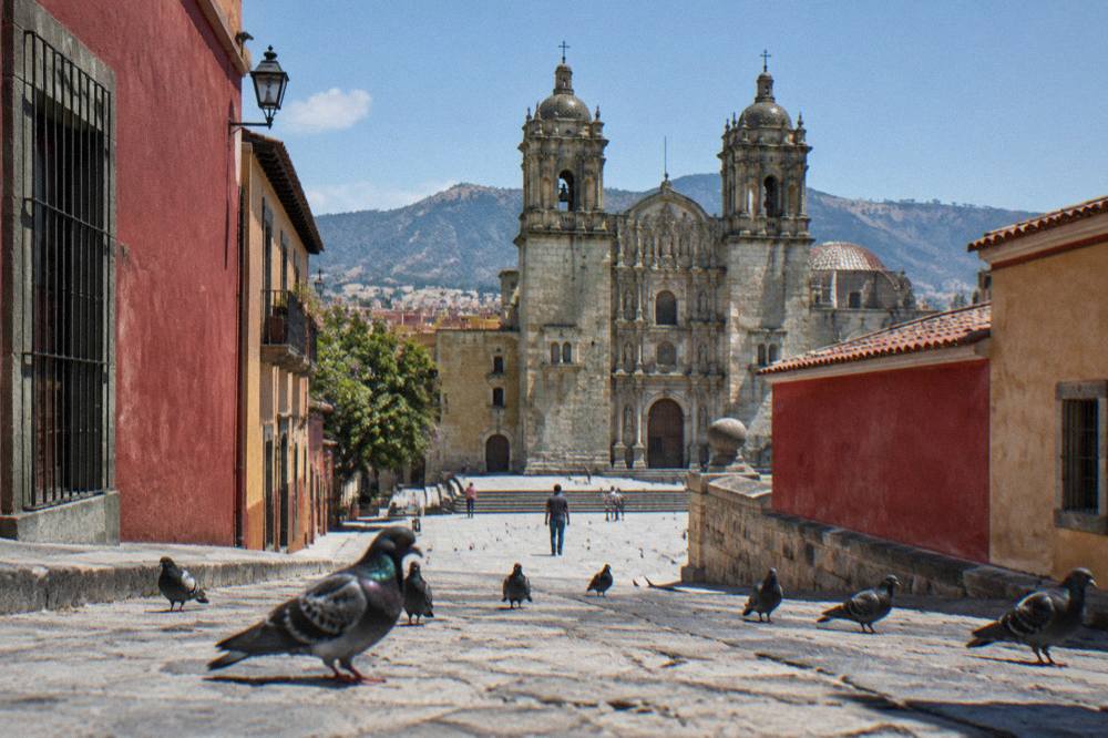 A street in central Oaxaca City with the Basílica de la Soledad towers rising behind rooftops