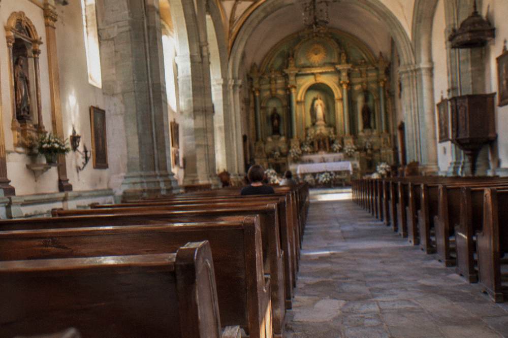 The interior of a church in Oaxaca City with rows of wooden pews facing the altar