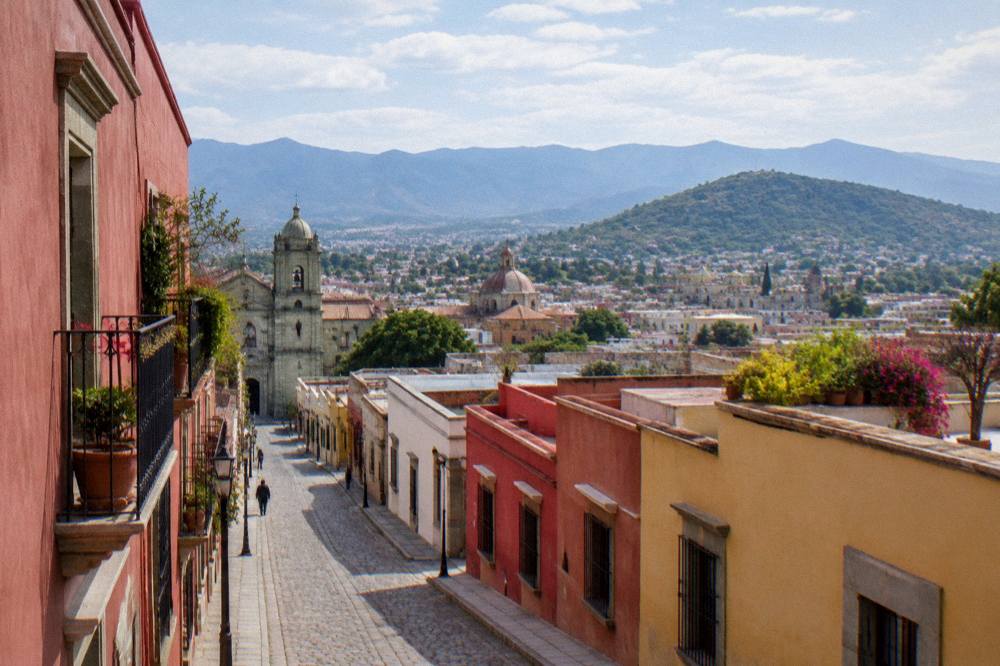 A wide view over the rooftops, domes and distant mountains of the Oaxaca valley from a hillside terrace