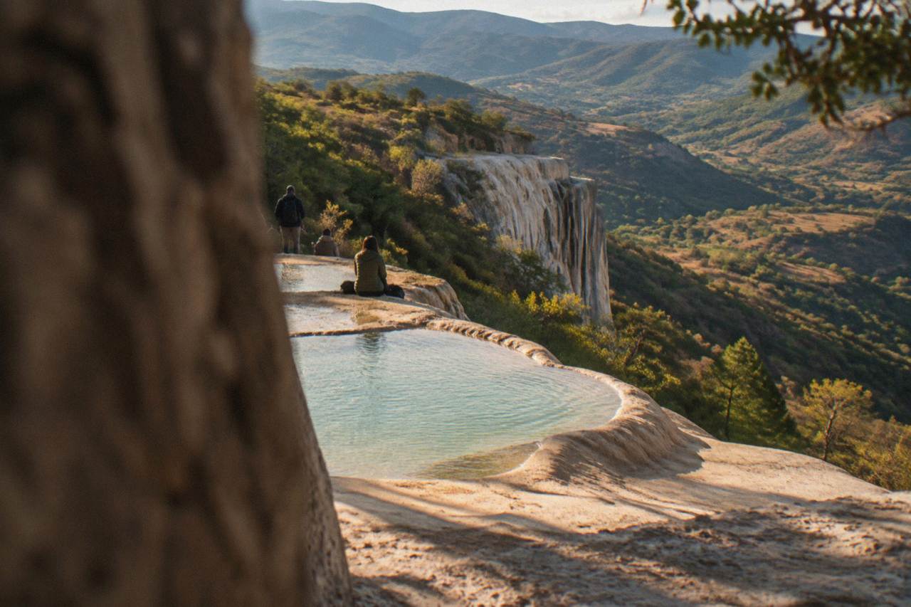 Mineral terraces and a petrified waterfall wall above a green valley in the mountains near Oaxaca