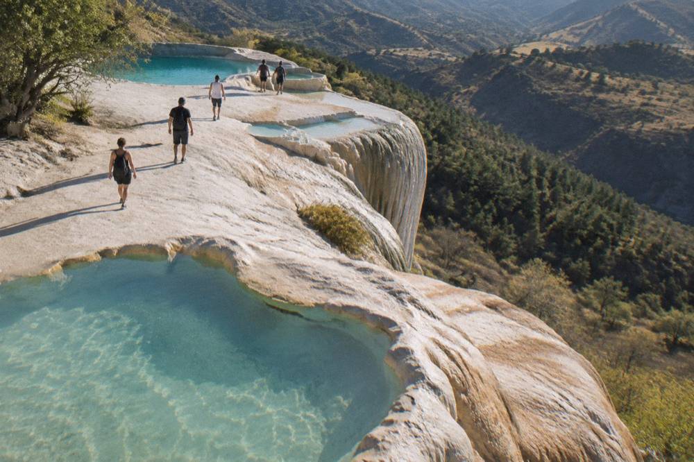 Travellers walking along the mineral terraces at the top of the Hierve el Agua cliffs
