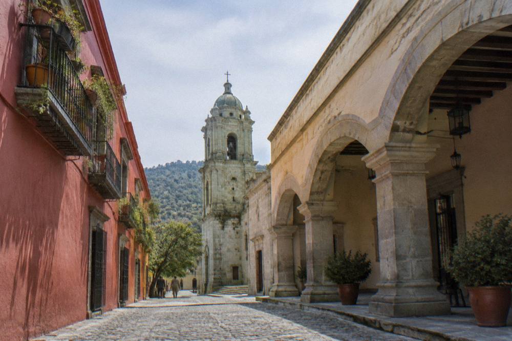 A shaded plaza with stone arches near an old convent building in Oaxaca City