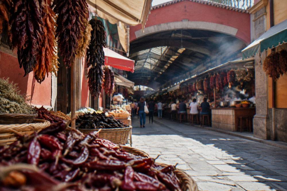 A pedestrian shopping street with market awnings leading toward a covered market in Oaxaca City