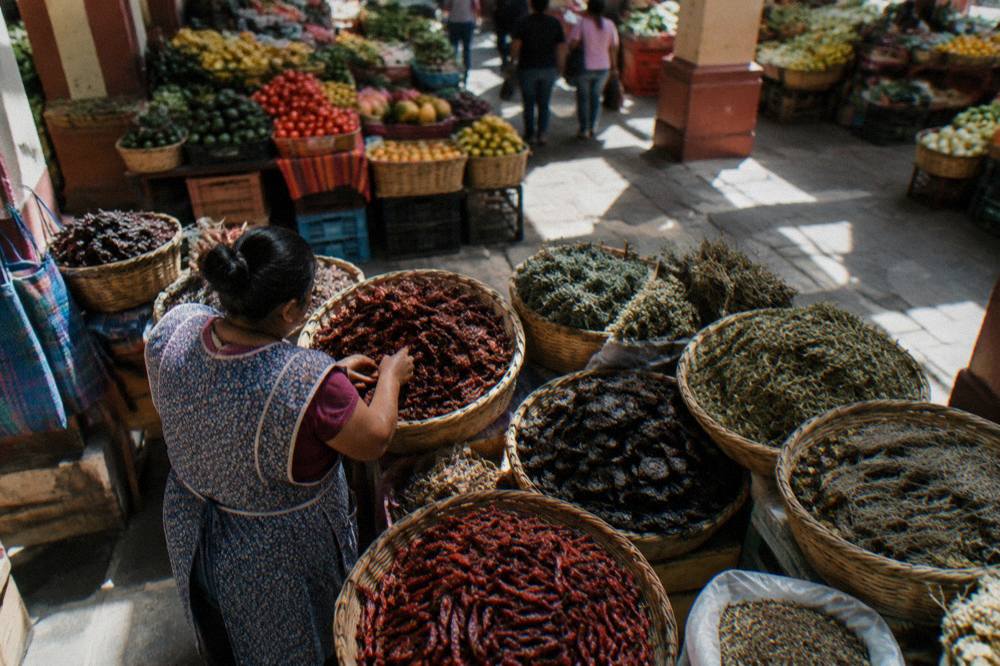 A vendor arranging chillies and dried herbs in baskets at a market stall