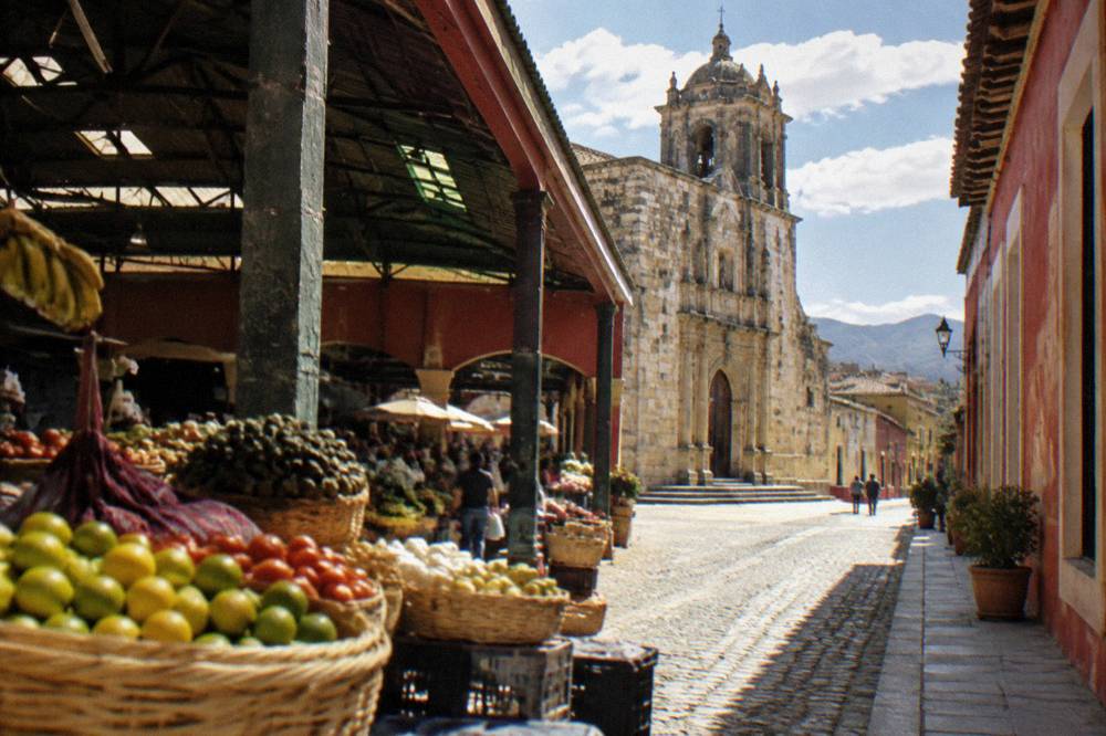 Sunlit colonial street with a stone church facade near the central market