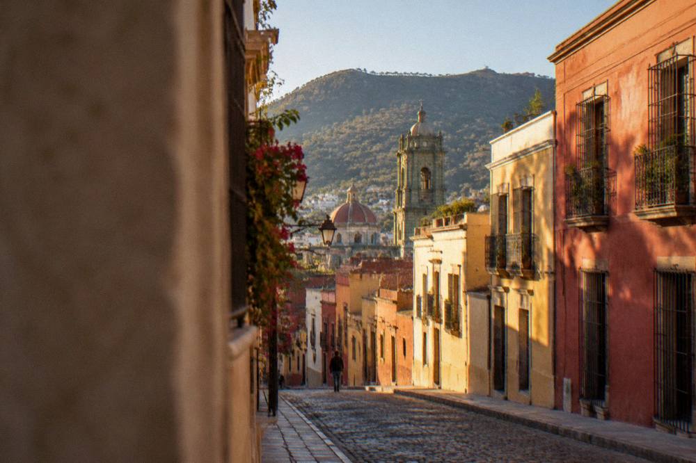 View over rooftops and church domes of Oaxaca's historic centre toward distant hills
