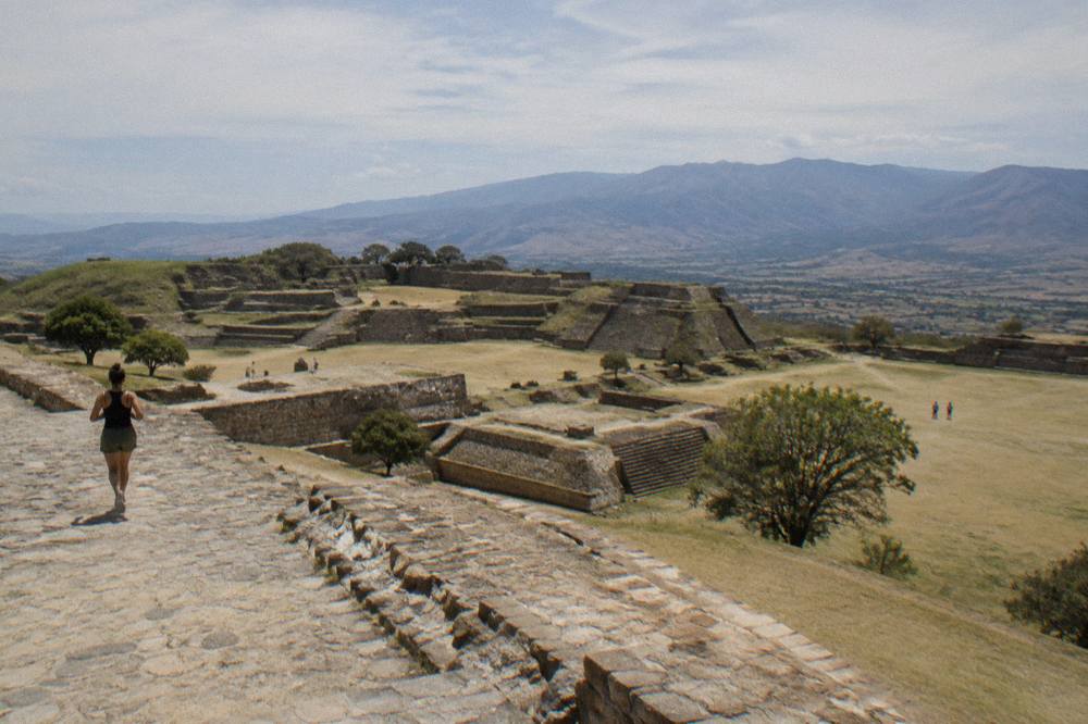 A view from a high ruin terrace across a broad valley toward distant mountains