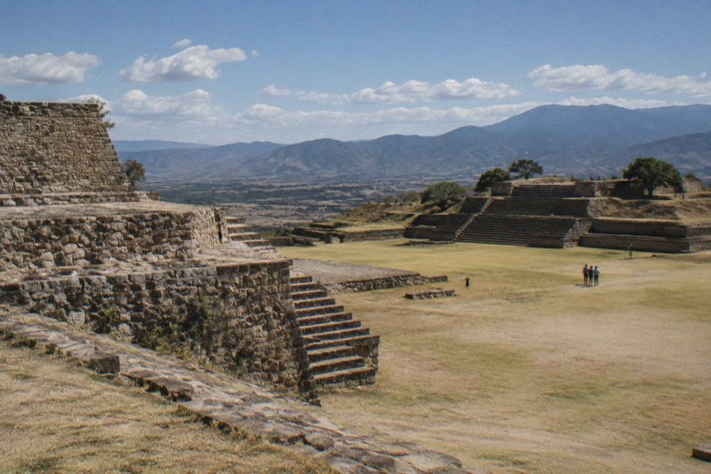 Late afternoon light across a mountaintop archaeological plaza with long shadows