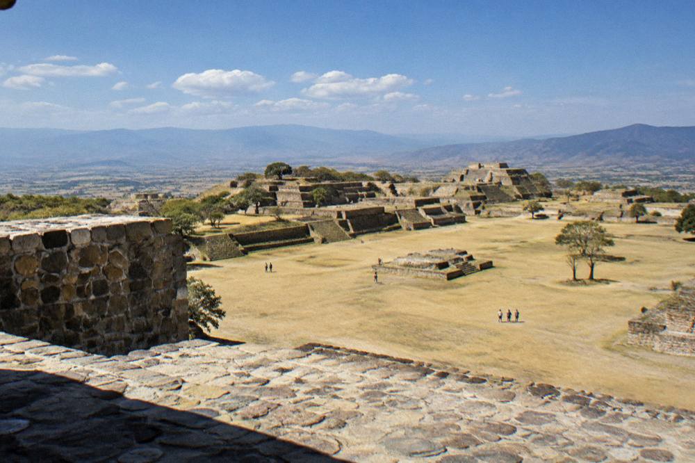 A wide panorama of terraced ruins and valley haze seen from a high stone platform