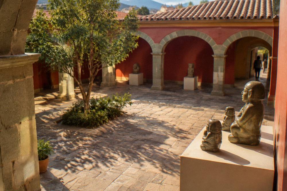 Polished pre-Hispanic stone figures arranged on a museum plinth under spotlights