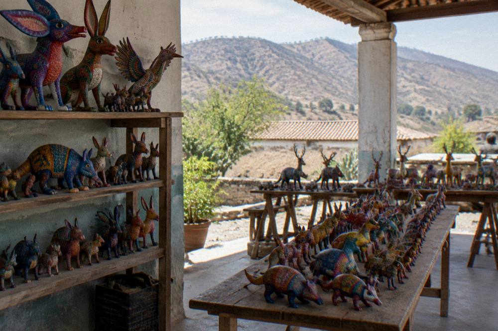 Colourful hand-painted alebrije animal figures displayed on shelves in a workshop
