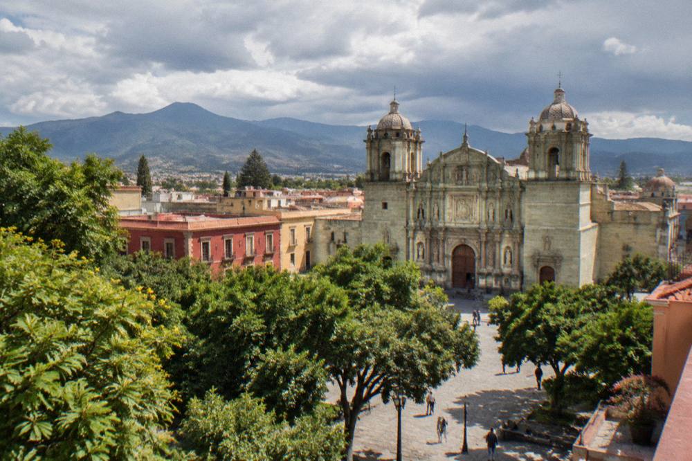 Rain clouds gathering over rooftops of a colonial city with mountains behind