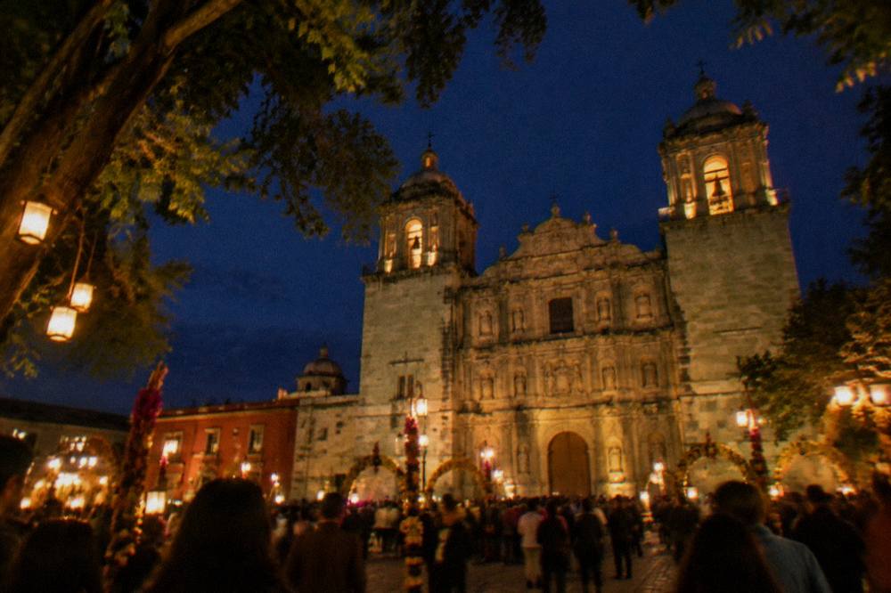 A crowd filling a city square at night with lanterns and decorated arches