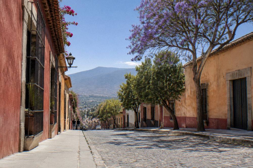 A quiet city street with coloured walls and mountains in the distance