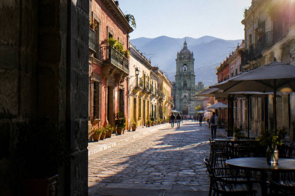 A stone pedestrian street lined with green cantera buildings leading away from a plaza