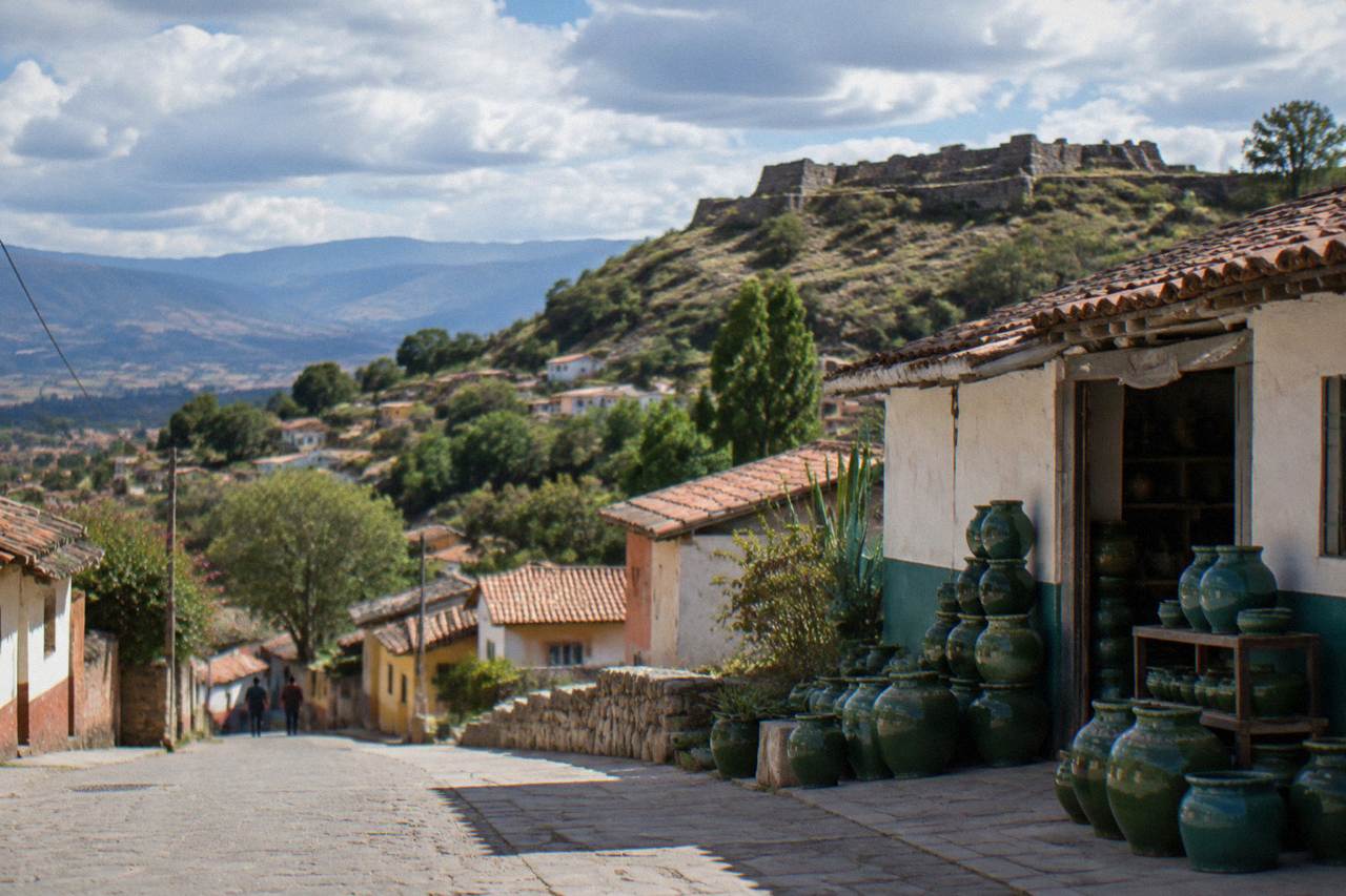 A hillside village of low houses and green trees above a valley in the Oaxaca Valles Centrales