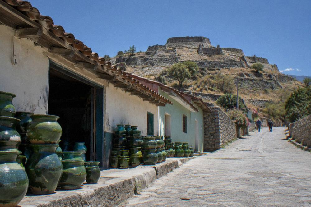 Stone terraces and low walls of an archaeological site on a hilltop above a wide valley